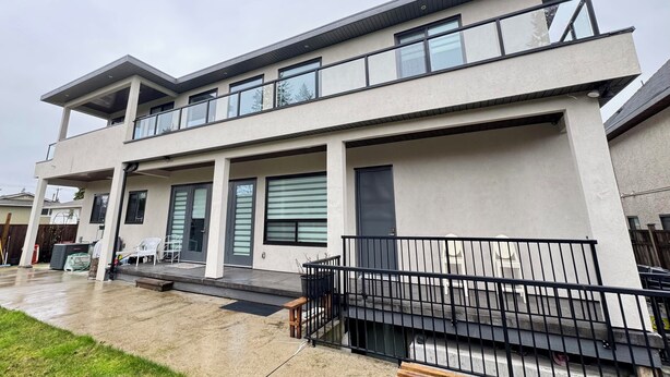 A modern two-story house with a balcony, large windows, and a concrete patio. - Excellent Place to Stay (Coquitlam)
