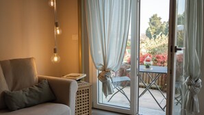 A room with a sofa, a small table, a basket, and a view through a glass door to an outdoor area with a table and chairs. - WellHome Asti (Asti)
