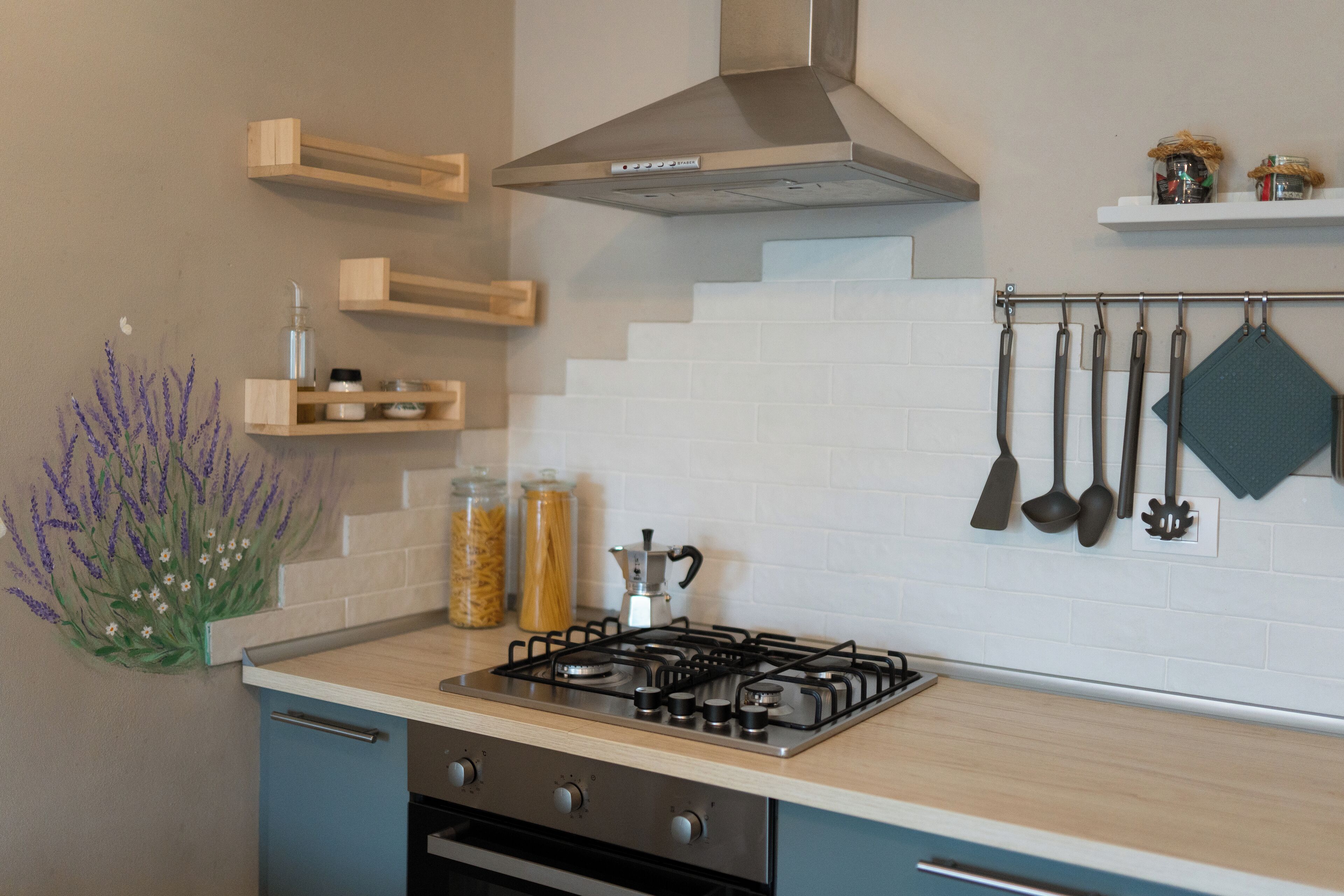 A modern kitchen with a gas stove, wooden shelves, and hanging kitchen utensils.