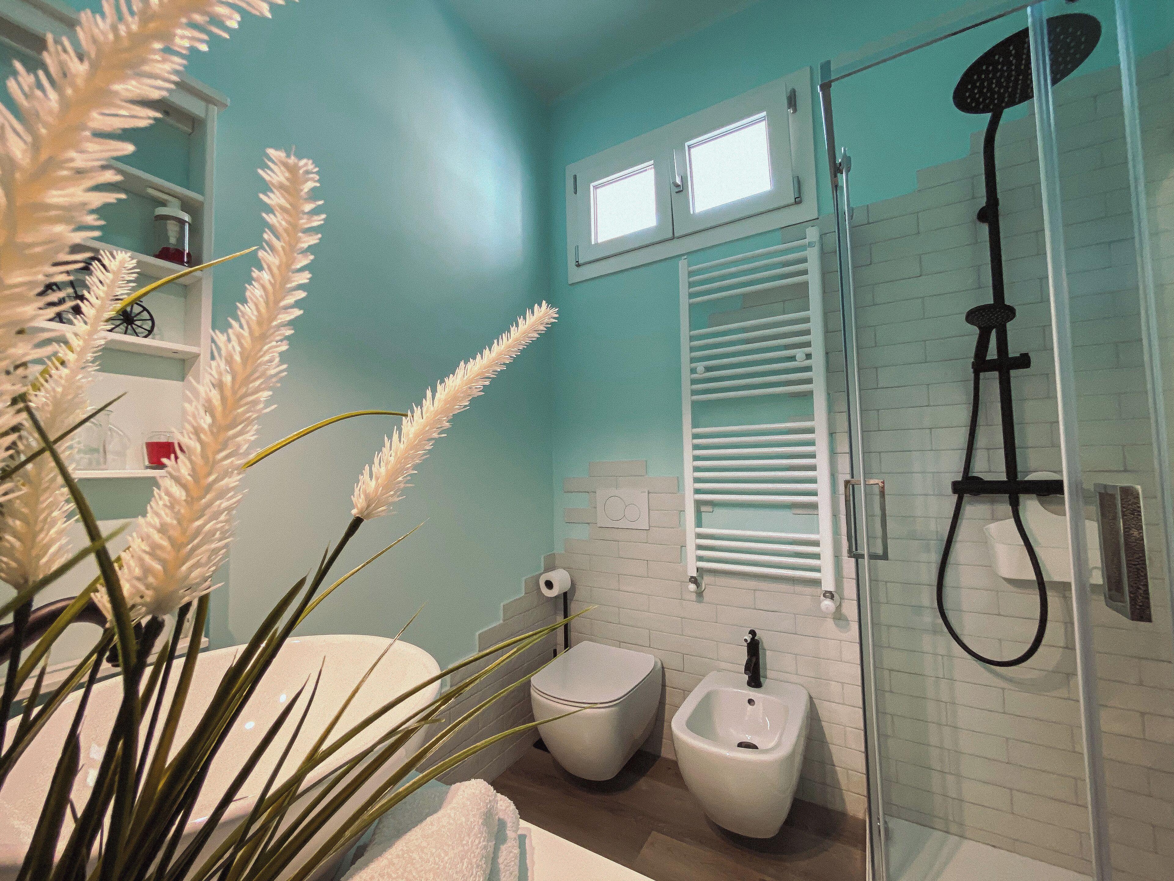 Un baño con ducha, bidé y una ventana sobre el inodoro.