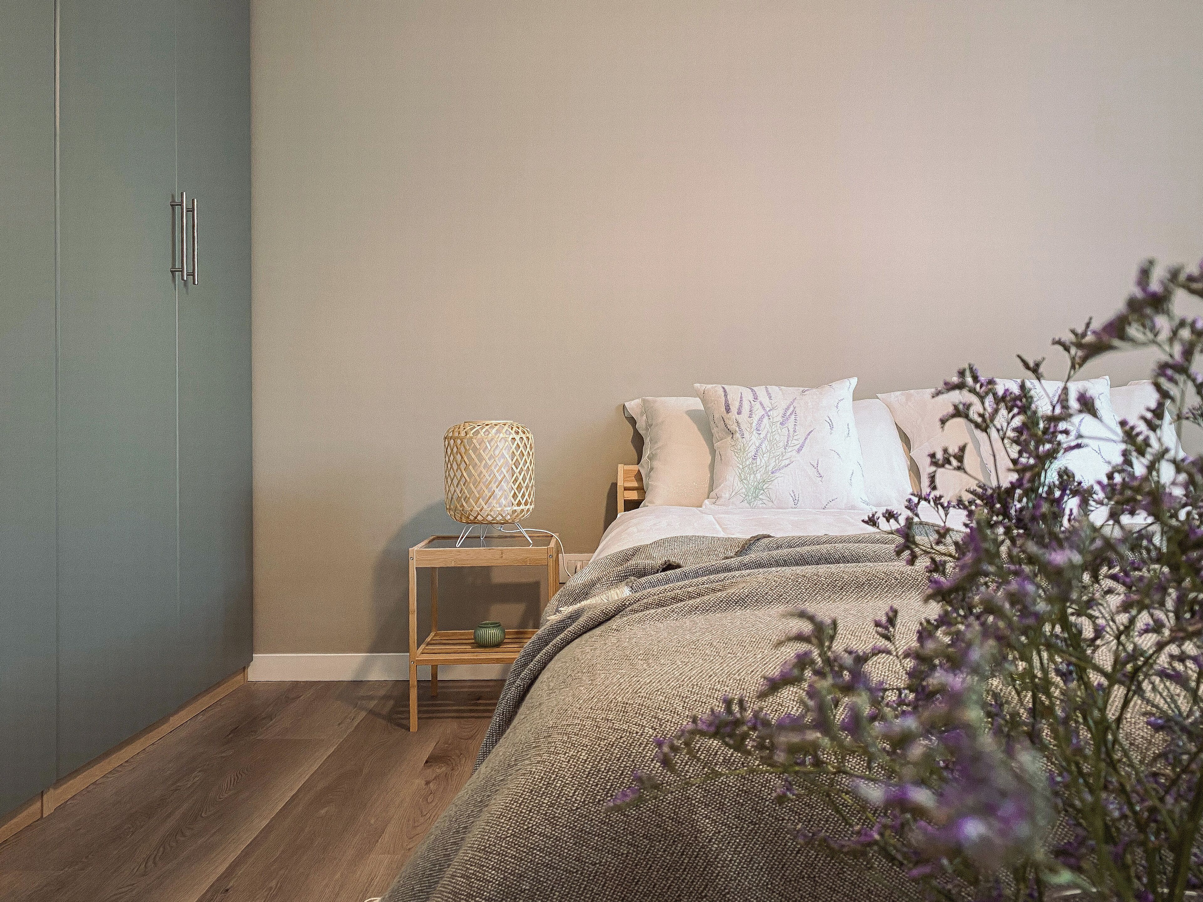 A bedroom with a bed, a nightstand, a lamp, and a wardrobe.
