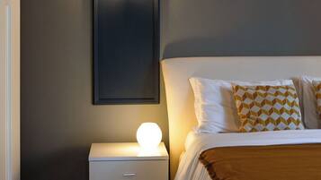 A bedroom with a bed, bedside table, and a wall-mounted light fixture.