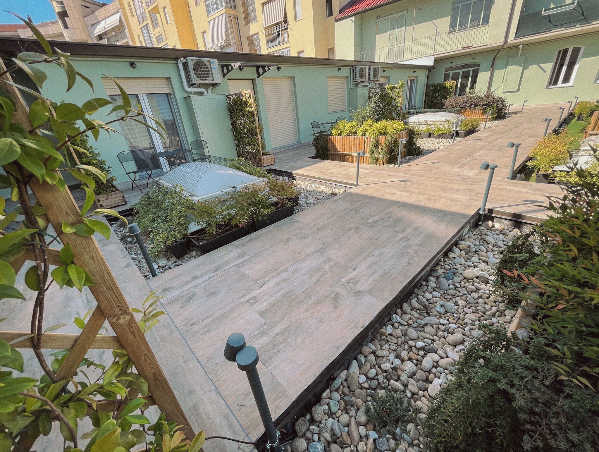 Un cortile con un pavimento in legno, piante in vaso e un piccolo angolo relax.