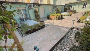 A courtyard with a wooden deck, potted plants, and a small seating area.
