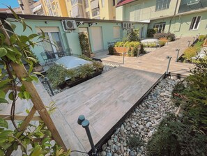 A courtyard with a wooden deck, potted plants, and a small seating area. - WellHome Asti (Asti)