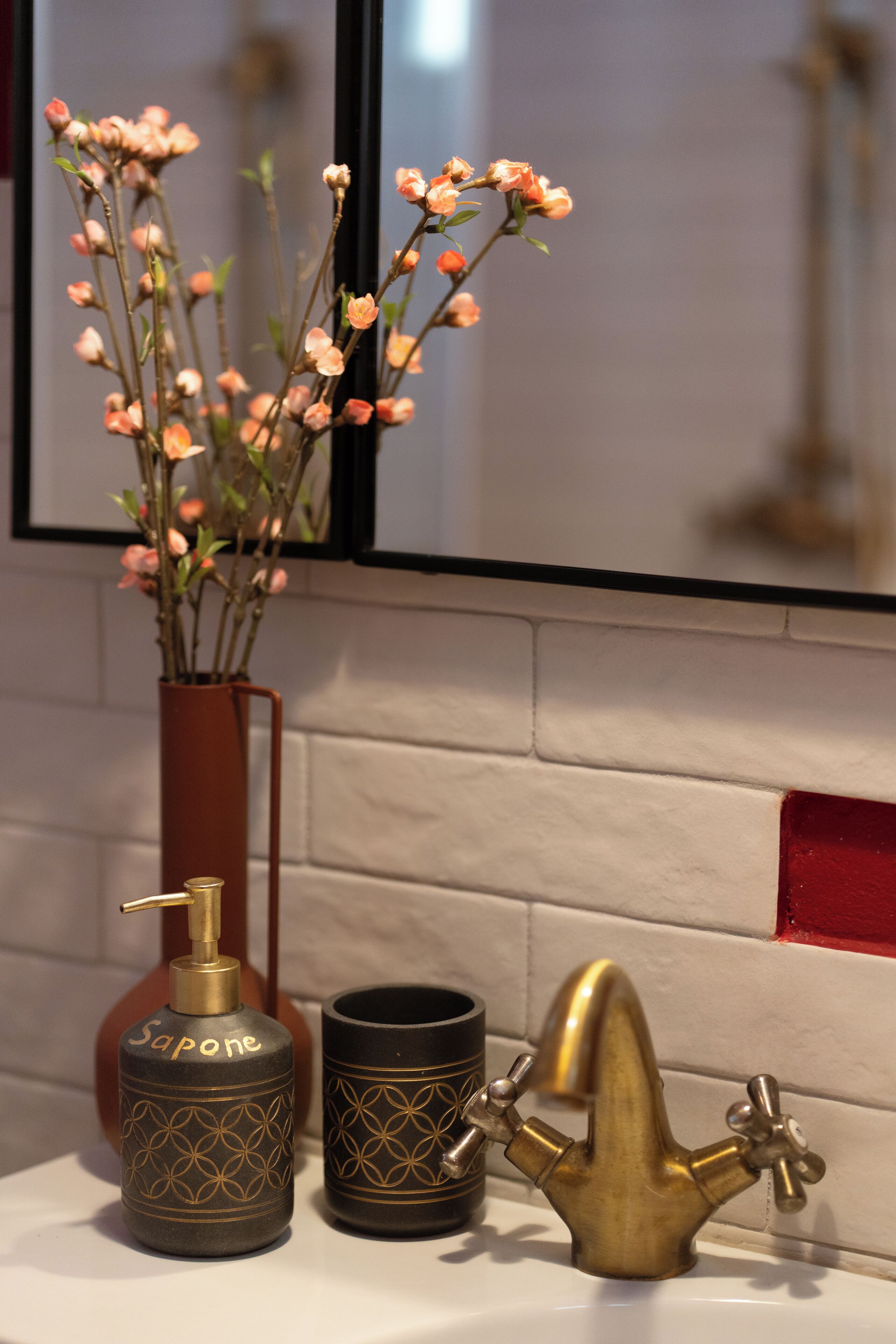 A bathroom vanity with a vase of flowers, a soap dispenser, and a faucet.