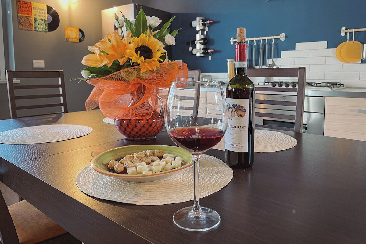 A dining table with a wine glass, a bottle of wine, and a bowl of snacks.