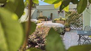 A courtyard with a small garden, a table, and a chair.