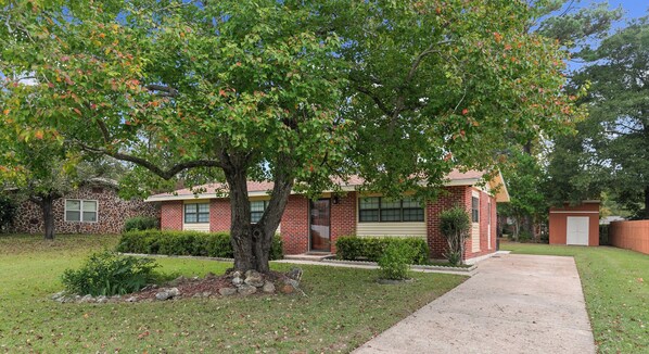 A two-story brick house with a front yard, a driveway, and a small garage. - 3/1.5 Southern Grace (Dothan)
