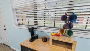 Uma cozinha com cafeteira, micro-ondas e uma fruteira sobre um balcão de madeira.