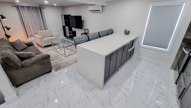 Uma sala de estar moderna com um sofá, uma mesa de centro e uma área de jantar com mesa e cadeiras.