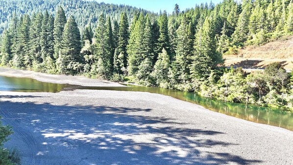 Un sendero de grava que bordea un río, con un denso bosque a un lado.