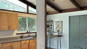 Eine moderne Küche mit Holzschränken, einem großen Spiegel und einem Essbereich mit Tisch und Stühlen.