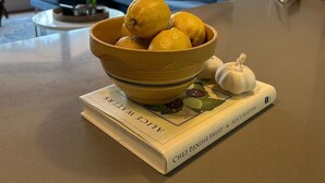 Eine Küchenarbeitsplatte mit einer Zitronenschale, einer Knoblauchbirne und einem Kochbuch mit dem Titel Alice Waters.