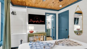 Ein Schlafzimmer mit Bett, Schreibtisch, Stuhl, Spiegel und einer Tür.