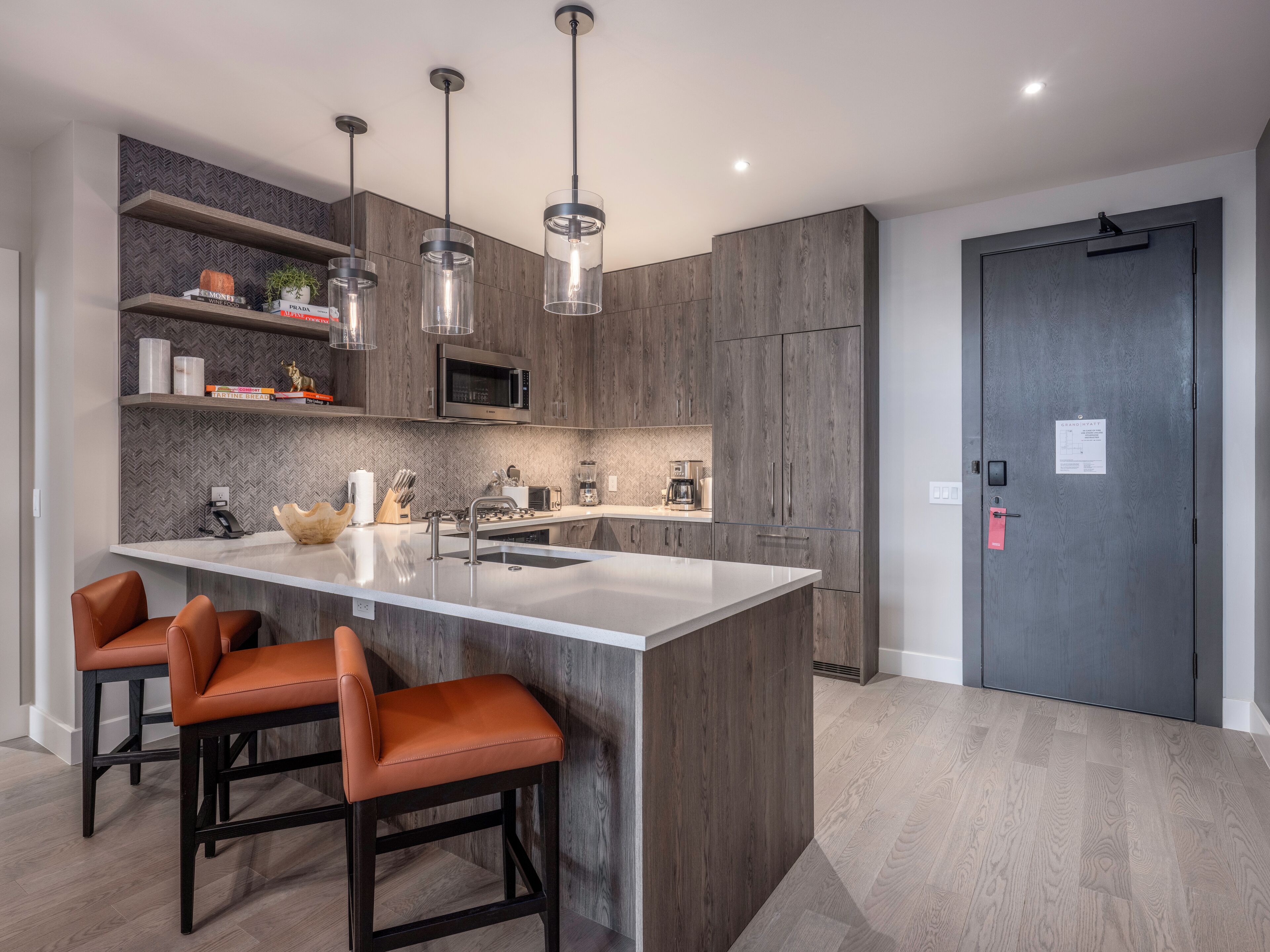 Una cucina moderna con isola centrale, sgabelli da bar, forno a microonde e luci a sospensione.
