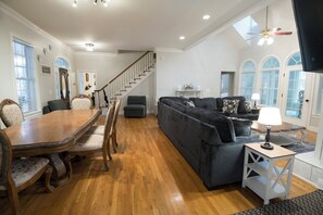A spacious living room with a wooden dining table, grey sofa, and a staircase leading to another level. - Southern feel 4-bedroom 3.5 bath house with over 4,000sq/ft of space to relax. (Carrollton)