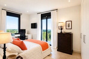 Ein Hotelzimmer mit Bett, Schreibtisch, Stuhl, Fernseher, Kommode und großen Fenstern mit Blick.