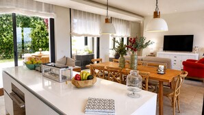 Une cuisine moderne dotée d’un grand îlot central, d’un coin repas et d’un salon avec un téléviseur.