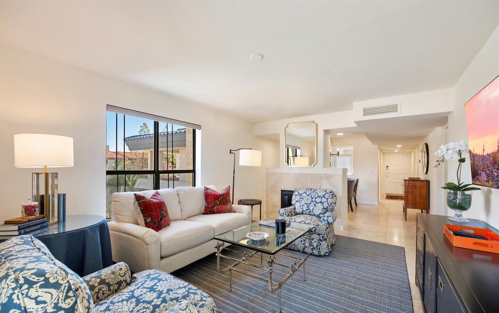 A spacious living room with a sofa, armchairs, a coffee table, and a dining area in the background.