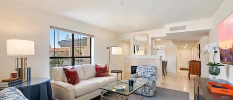A spacious living room with a sofa, armchairs, a coffee table, and a dining area in the background.