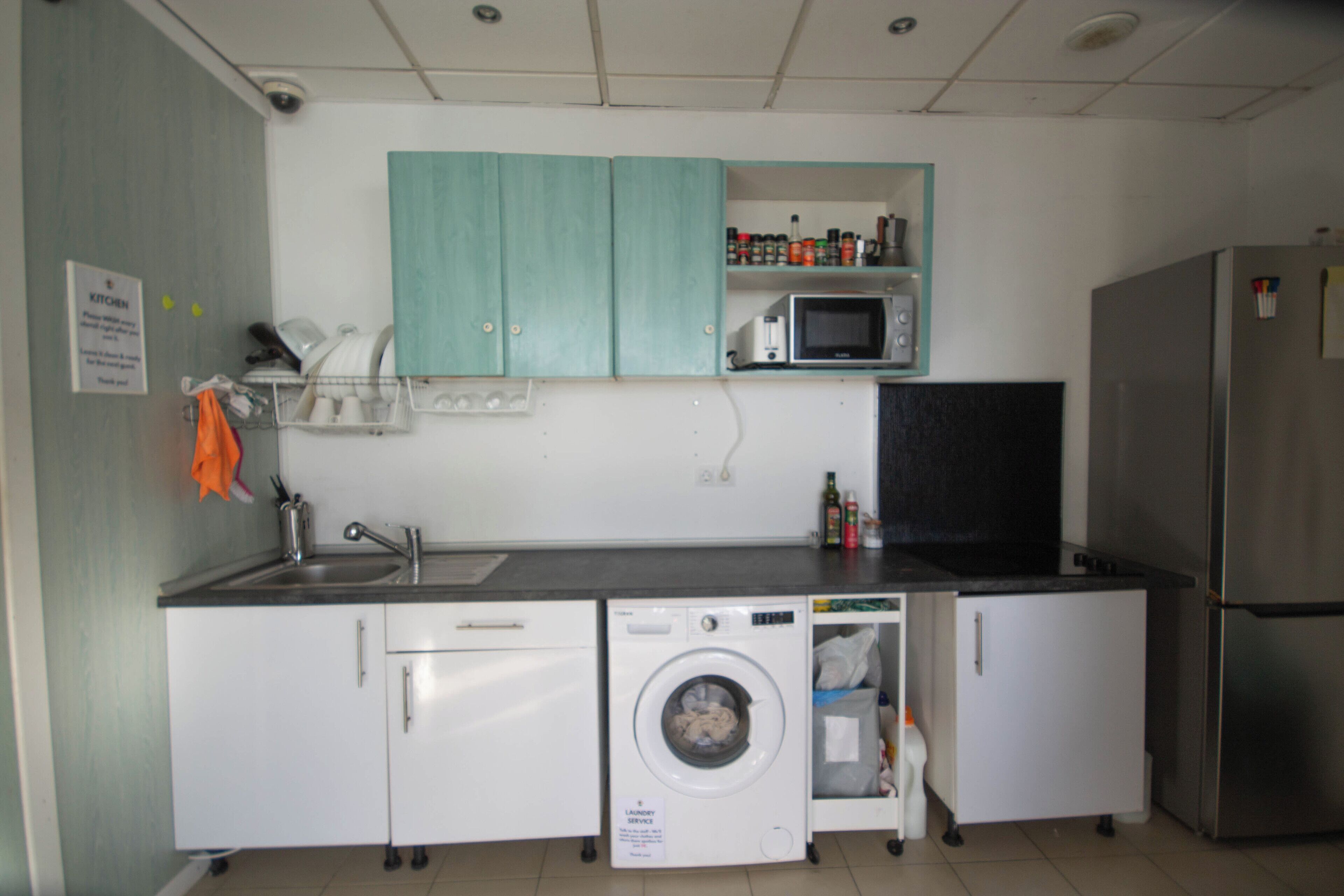Uma cozinha compacta com máquina de lavar, micro-ondas e frigorífico.