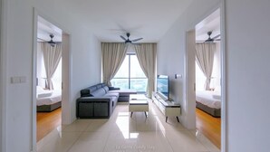 Una habitación de hotel moderna con sofá, televisión y balcón con cortinas.