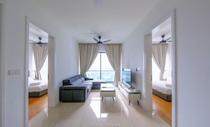 Habitació d'hotel moderna amb sofà, televisió i un balcó amb cortines.