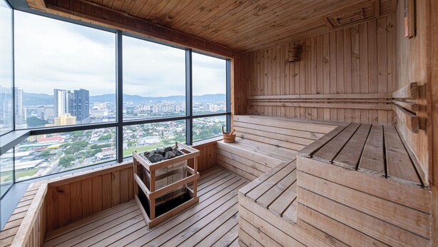 Una sauna de madera con amplios ventanales que ofrecen vistas a la ciudad.