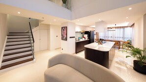 Un interior moderno con una escalera, una isla de cocina y una zona de estar.