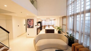 Una sala moderna con un sofá curvo, un comedor y una cocina al fondo.