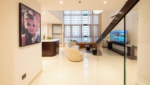 Una sala de estar moderna con un sofá curvo, un televisor de pantalla plana y una escalera.