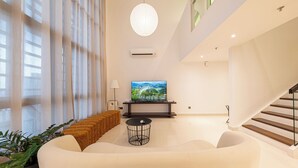 Una sala de estar moderna con un sofá grande, una mesa redonda de centro y un televisor de pantalla plana sobre un mueble.