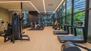 Ein modernes Fitnessstudio mit unterschiedlichen Trainingsgeräten, großen Fenstern und Blick ins Grüne.