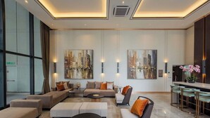 Eine moderne Hotelhalle mit Ecksofa, rundem Couchtisch und einer Bar mit Hockern.