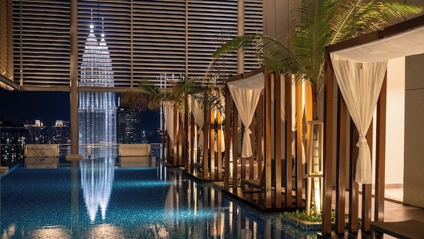A modern indoor pool with a city skyline view, surrounded by wooden structures and palm trees. - Luxe 3R2B Pav Ceylon Bukit Bintang KLCC 600MBPS (Kuala Lumpur)