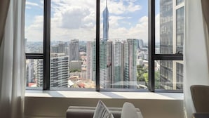 A room with a large window offering a city view, including a prominent skyscraper. - Luxe 3R2B Pav Ceylon Bukit Bintang KLCC 600MBPS (Kuala Lumpur)