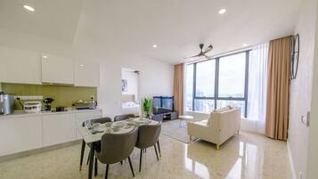 Eine moderne Wohnung mit Essbereich, Küche, Wohnzimmer und großen Fenstern mit Blick auf die Stadt.