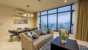 Ein modernes Wohnzimmer mit Sofa, Couchtisch und Essbereich. Ein großes Fenster bietet Blick auf die Stadt.