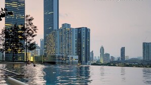 A swimming pool with a lounge chair in the foreground and a city skyline in the background. - 2BR Luxury Living KLCC 600mbps (Kuala Lumpur)