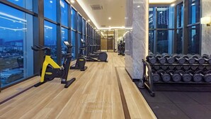 A modern gym with cardio equipment, weight racks, and large windows offering city views. - 2BR Luxury Living KLCC 600mbps (Kuala Lumpur)
