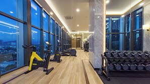 Ett modernt gym med konditionsmaskiner, vikter och stora fönster med utsikt över staden.