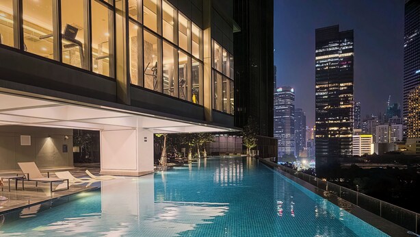 Ein Pool auf dem Dach mit Blick auf die Stadt, moderne Architektur und ein gut beleuchteter Innenraum.