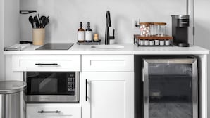 Una cocina moderna con armarios blancos, microondas, horno, cafetera y lavavajillas.