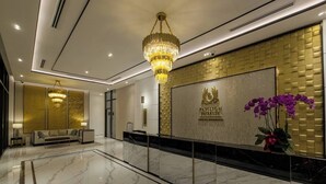 En moderne lobby med en receptionsdisk, en lysekrone og en receptionsvæg med Pavilion Embassy logo.