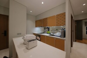 A modern kitchen with white countertops, a built-in oven, a coffee maker, and wooden cabinets. - 3R2B SkySuites Next to KLCC Twin Tower High Floor (Kuala Lumpur)