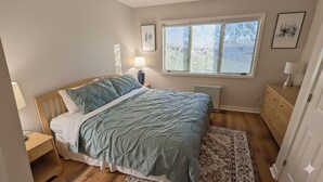 A bedroom with a bed, bedside tables, a window, a radiator, and a dresser. - Chic Stratton Condo- Walking Distance to Village (Stratton)