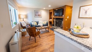 A living room with a fireplace, a television, and a dining area with a granite countertop. - Chic Stratton Condo- Walking Distance to Village (Stratton)
