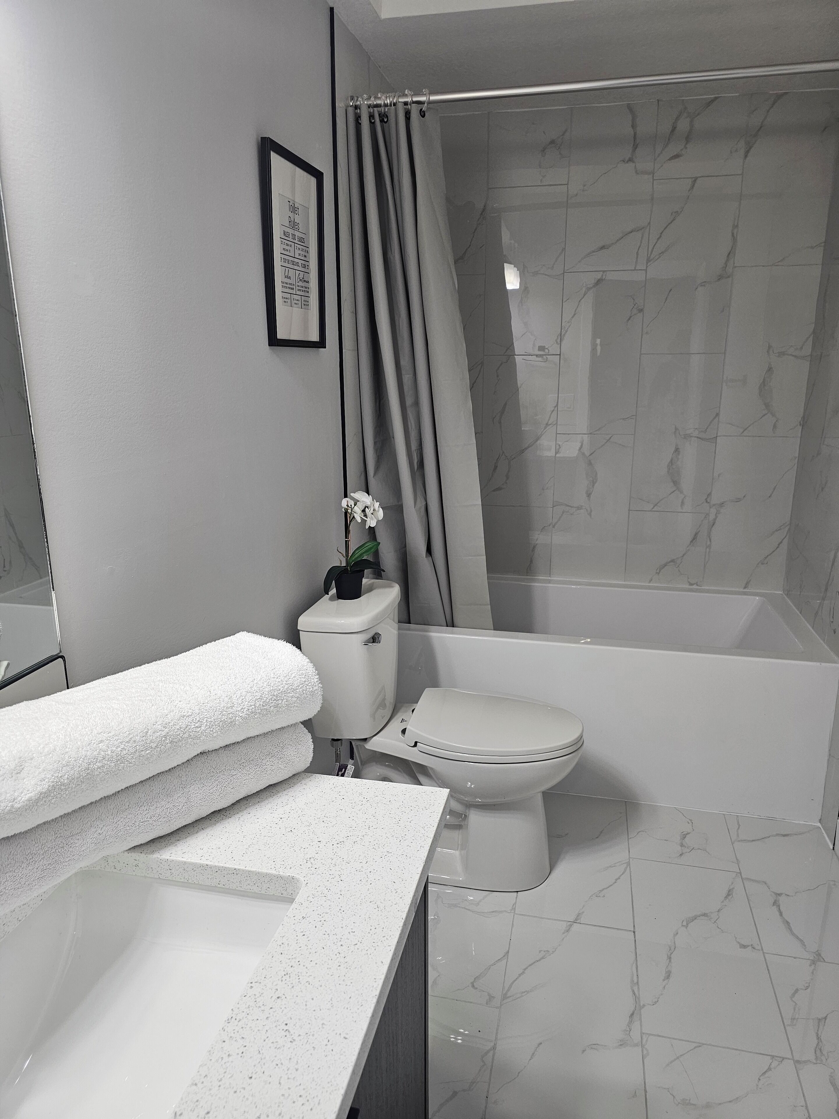 Een moderne badkamer met toilet, wastafel en bad.