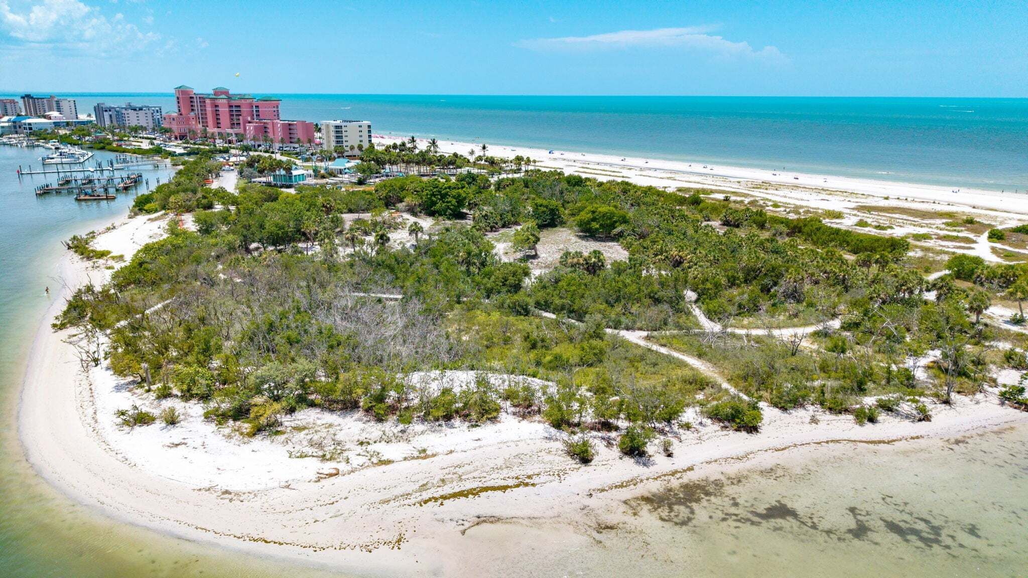 Une zone côtière avec une plage, un port de plaisance et des bâtiments en arrière-plan.